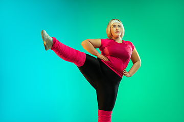 Image showing Young caucasian plus size female model\'s training on gradient green background