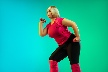 Image showing Young caucasian plus size female model\'s training on gradient green background