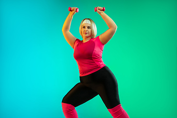 Image showing Young caucasian plus size female model\'s training on gradient green background