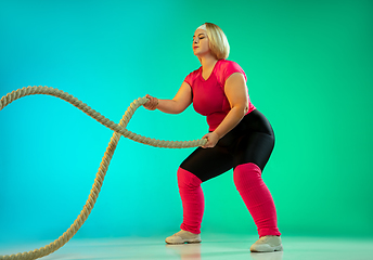 Image showing Young caucasian plus size female model\'s training on gradient green background