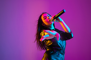 Image showing Caucasian female singer portrait isolated on purple studio background in neon light