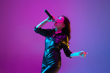 Image showing Caucasian female singer portrait isolated on purple studio background in neon light