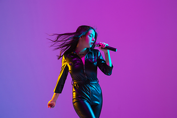 Image showing Caucasian female singer portrait isolated on purple studio background in neon light