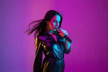 Image showing Caucasian female singer portrait isolated on purple studio background in neon light