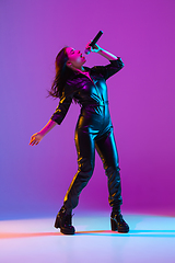 Image showing Caucasian female singer portrait isolated on purple studio background in neon light