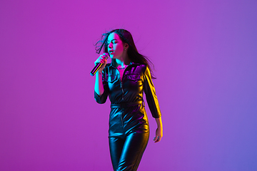 Image showing Caucasian female singer portrait isolated on purple studio background in neon light