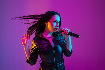 Image showing Caucasian female singer portrait isolated on purple studio background in neon light