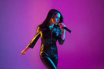 Image showing Caucasian female singer portrait isolated on purple studio background in neon light