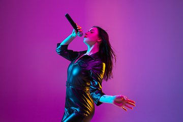 Image showing Caucasian female singer portrait isolated on purple studio background in neon light