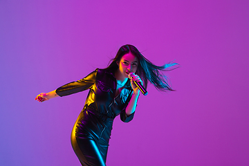 Image showing Caucasian female singer portrait isolated on purple studio background in neon light