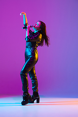 Image showing Caucasian female singer portrait isolated on purple studio background in neon light