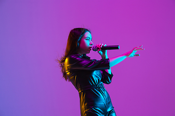 Image showing Caucasian female singer portrait isolated on purple studio background in neon light