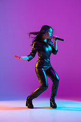 Image showing Caucasian female singer portrait isolated on purple studio background in neon light