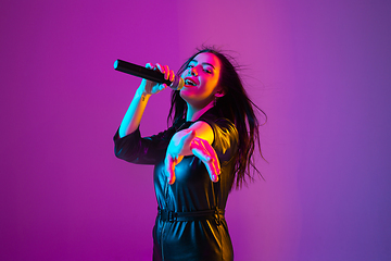 Image showing Caucasian female singer portrait isolated on purple studio background in neon light