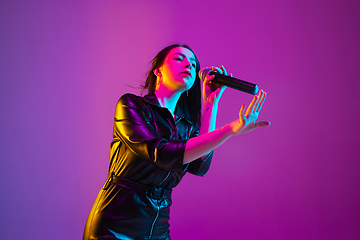 Image showing Caucasian female singer portrait isolated on purple studio background in neon light