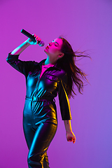 Image showing Caucasian female singer portrait isolated on purple studio background in neon light