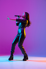 Image showing Caucasian female singer portrait isolated on purple studio background in neon light