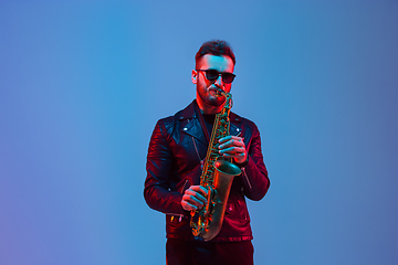 Image showing Young caucasian jazz musician playing the saxophone in neon light