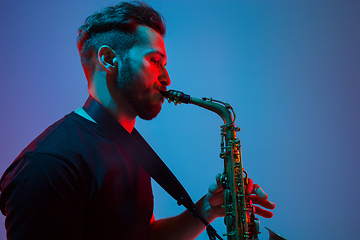 Image showing Young caucasian jazz musician playing the saxophone in neon light