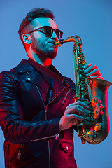 Image showing Young caucasian jazz musician playing the saxophone in neon light