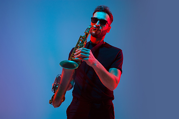 Image showing Young caucasian jazz musician playing the saxophone in neon light