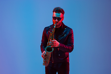 Image showing Young caucasian jazz musician playing the saxophone in neon light