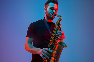 Image showing Young caucasian jazz musician playing the saxophone in neon light