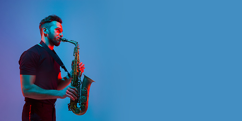 Image showing Young caucasian jazz musician playing the saxophone in neon light, flyer