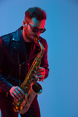 Image showing Young caucasian jazz musician playing the saxophone in neon light