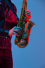 Image showing Young caucasian jazz musician playing the saxophone in neon light, close up