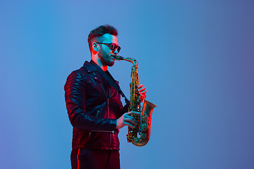 Image showing Young caucasian jazz musician playing the saxophone in neon light