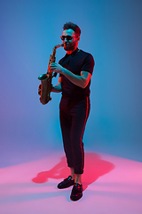 Image showing Young caucasian jazz musician playing the saxophone in neon light