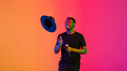 Image showing Young african-american musician singing, dancing in neon light, flyer