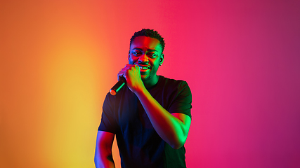 Image showing Young african-american musician singing, dancing in neon light