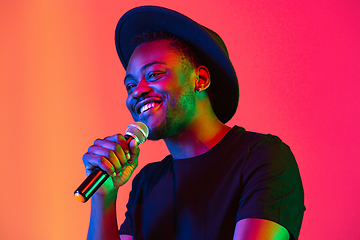 Image showing Young african-american musician singing, dancing in neon light