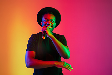 Image showing Young african-american musician singing, dancing in neon light