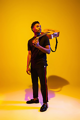 Image showing Young african-american musician singing, playing guitar in neon light