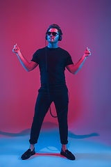 Image showing Young caucasian musician singing, dancing in neon light