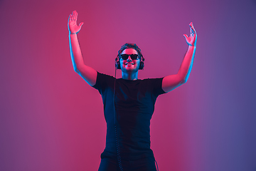 Image showing Young caucasian musician singing, dancing in neon light