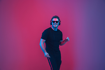 Image showing Young caucasian musician singing, dancing in neon light