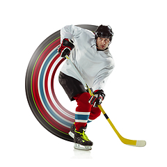 Image showing Young male hockey player with the stick on ice court and white background