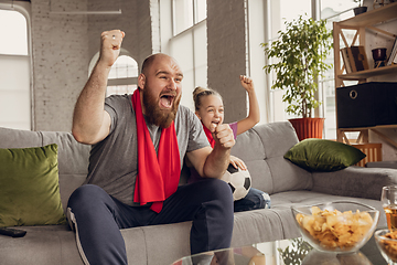 Image showing Excited, happy daughter and father watch football, soccer match together on the couch at home