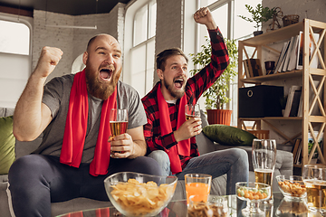 Image showing Excited, happy friends watch sport match together on the couch at home