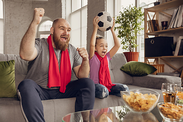 Image showing Excited, happy daughter and father watch football, soccer match together on the couch at home