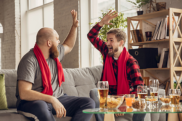 Image showing Excited, happy friends watch sport match together on the couch at home