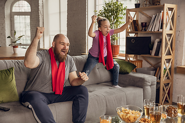 Image showing Excited, happy daughter and father watch football, soccer match together on the couch at home