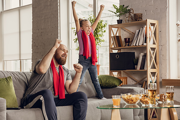 Image showing Excited, happy daughter and father watch football, soccer match together on the couch at home