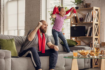 Image showing Excited, happy daughter and father watch football, soccer match together on the couch at home