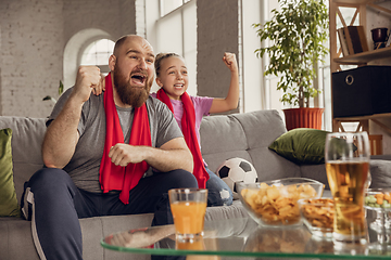 Image showing Excited, happy daughter and father watch football, soccer match together on the couch at home