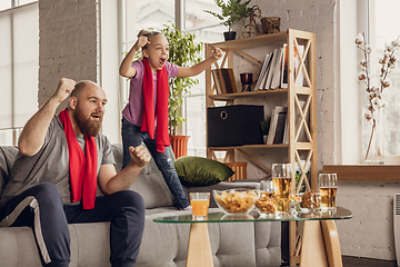 Image showing Excited, happy daughter and father watch football, soccer match together on the couch at home